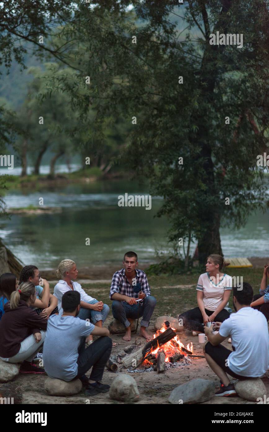 a group of happy young friends relaxing and enjoying summer evening ...