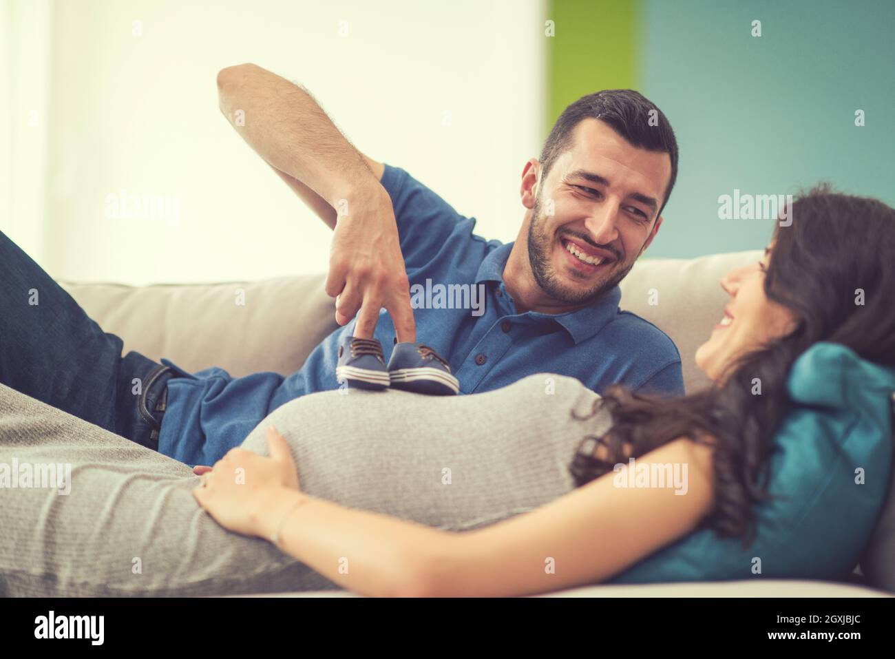 happy pregnant couple relaxing on sofa couch at home Stock Photo Alamy
