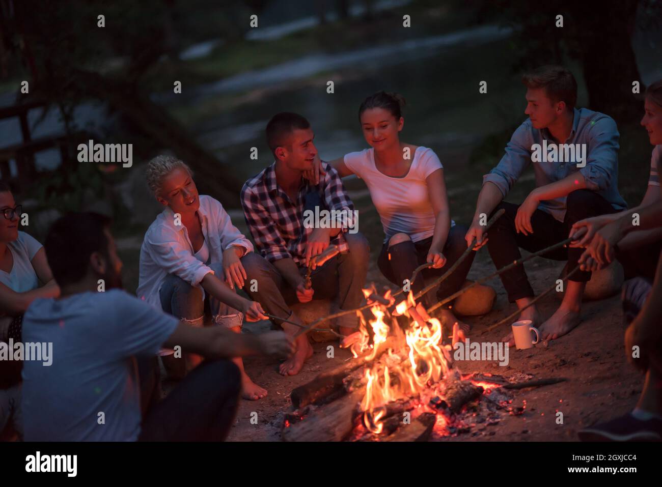 a group of happy young friends relaxing and enjoying summer evening ...