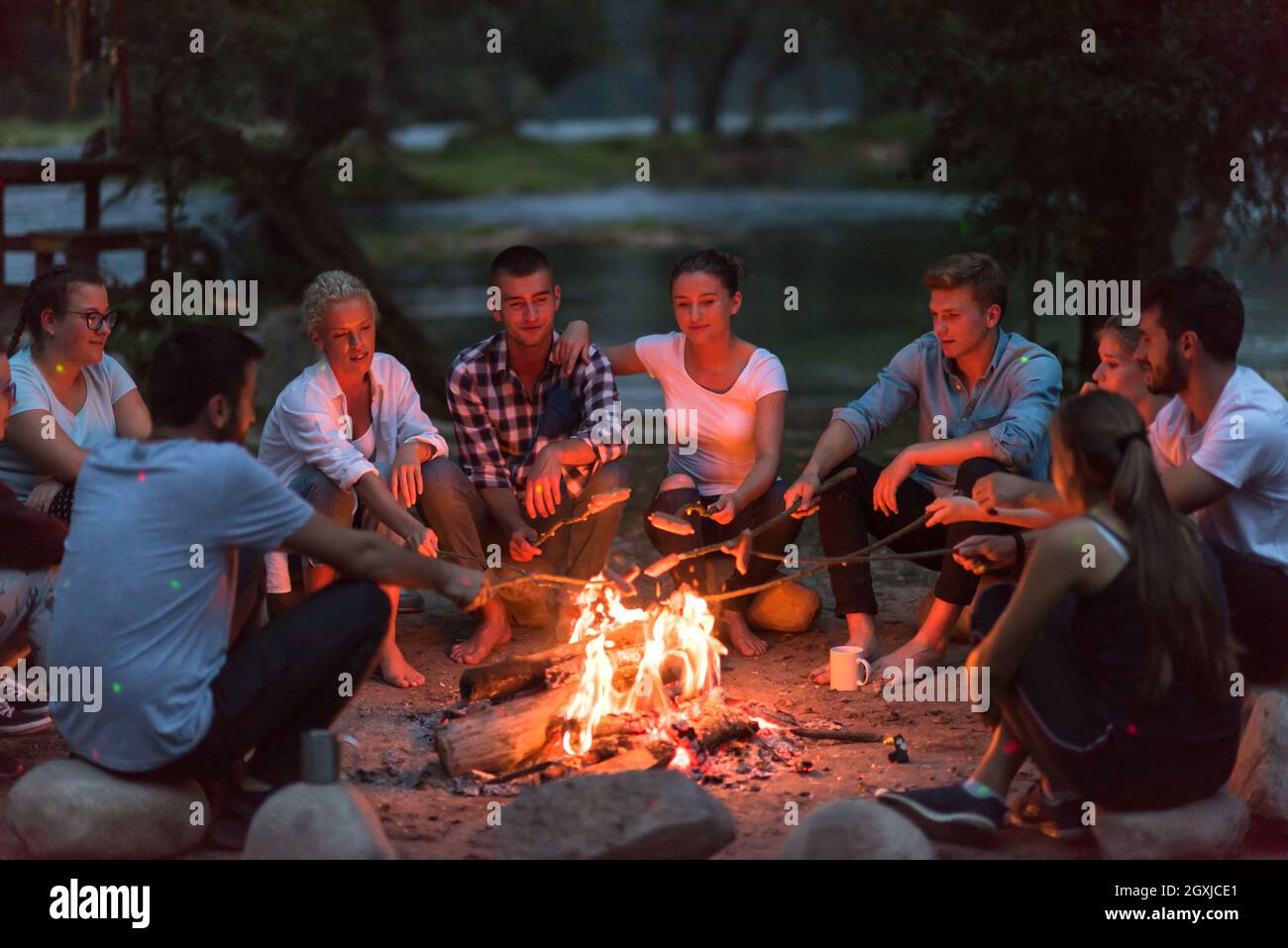 a group of happy young friends relaxing and enjoying summer evening ...