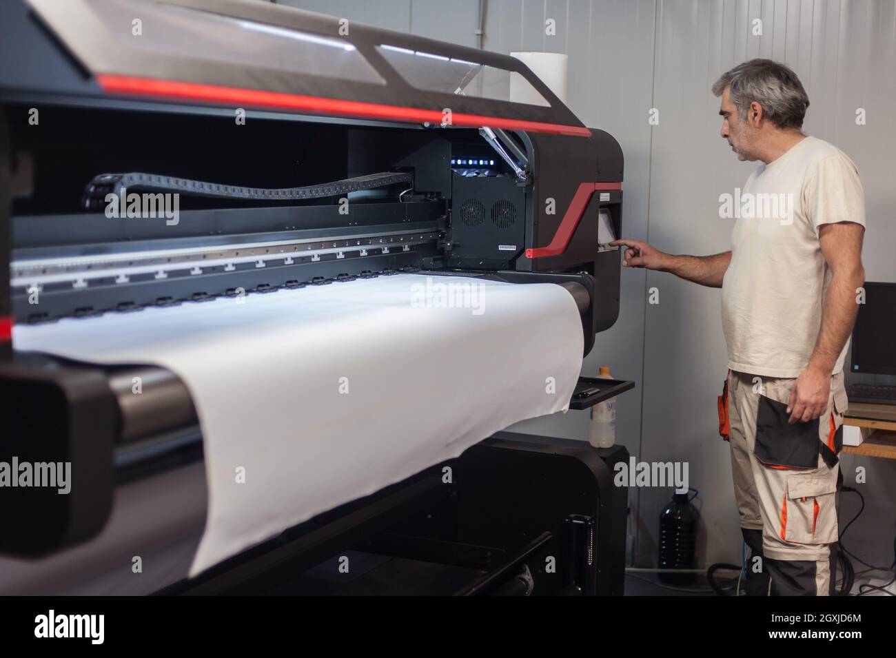Technician worker operator works on large premium industrial printer ...