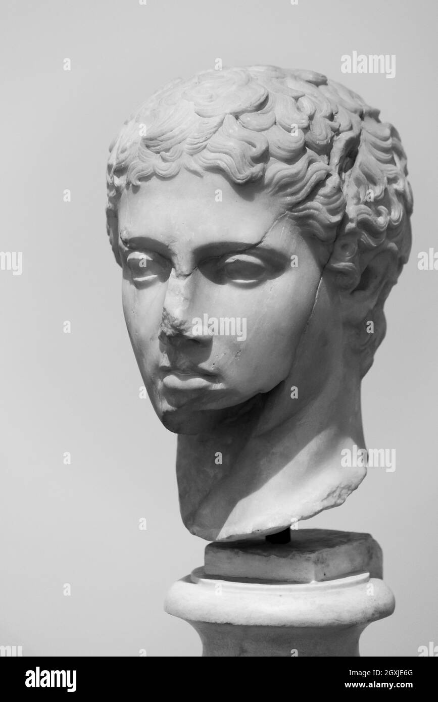 Black and white photo of marble head in ruins representing a young male roman Stock Photo