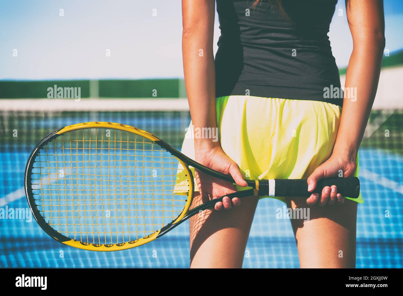 Back view of tennis player athlete woman holding racket against fashion skirt and back of thighs ready to play game on hard court playing match Stock Photo