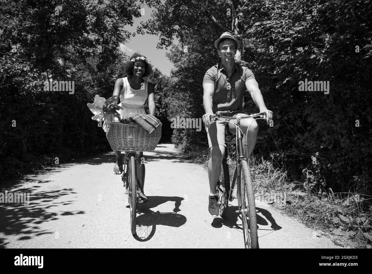 a young man and a beautiful African American girl enjoying a bike ride in nature on a sunny summer day Stock Photo