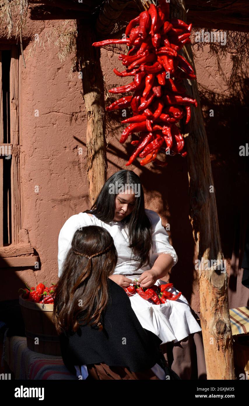 A woman demonstrates how to make ristras, or strings of chile peppers, at El Rancho de Las Golondrinas living history complex in New Mexico. Stock Photo