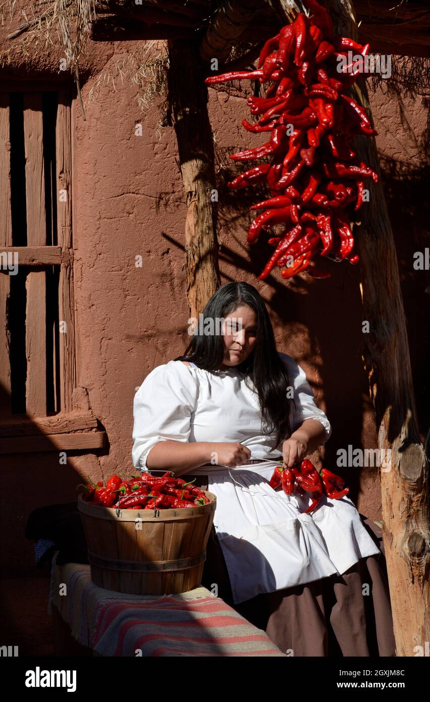 A woman demonstrates how to make ristras, or strings of chile peppers ...