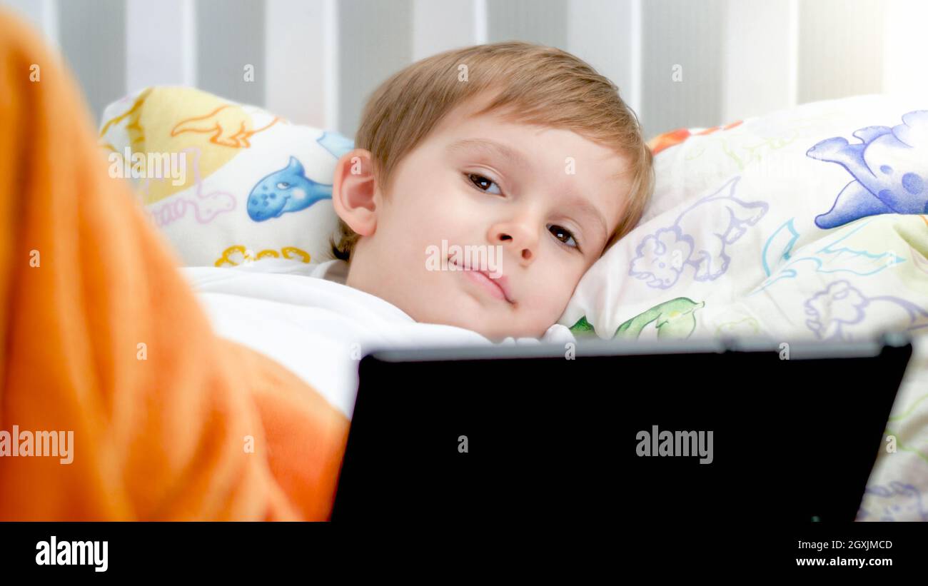Portrait of little smiling boy lying with digital tablet in bed Stock ...