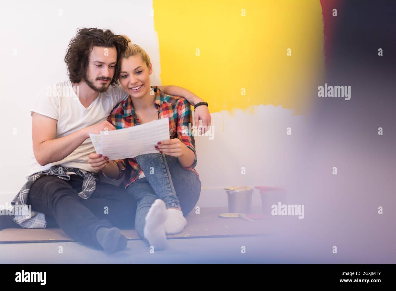 Happy young couple relaxing after painting a room in their new house on