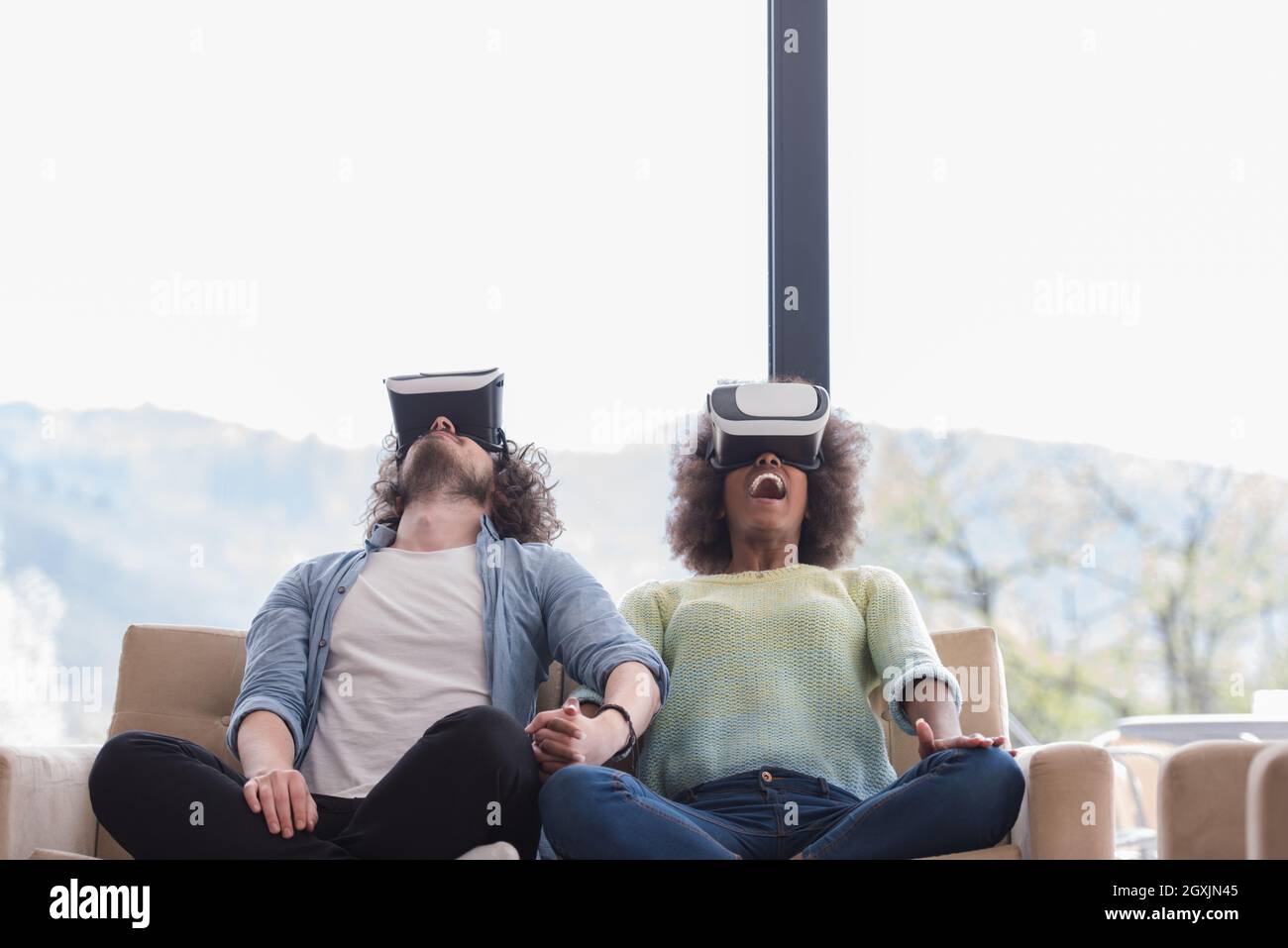 Multiethnic Couple using virtual reality headset in living room at home ...