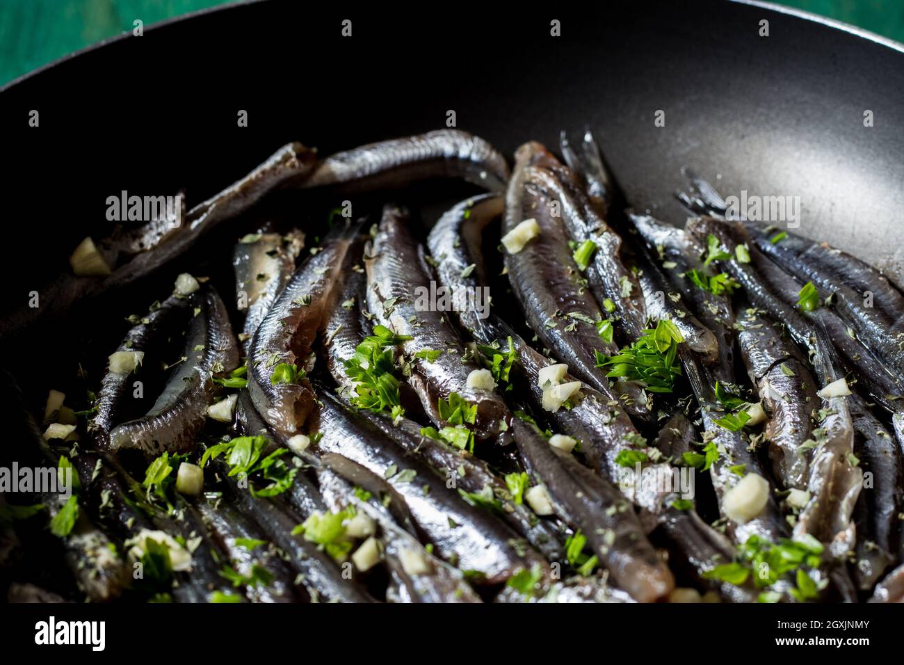Fresh anchovies to be cooked in a pan with garlic and parsley. Wood