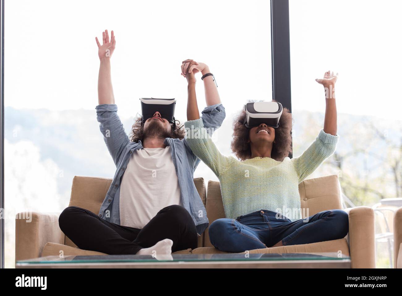 Multiethnic Couple using virtual reality headset in living room at home ...