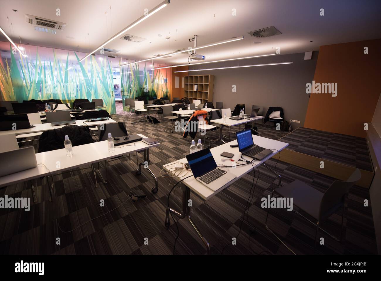 empty it classroom with program code on projector screen and modern laptop computers on table Stock Photo