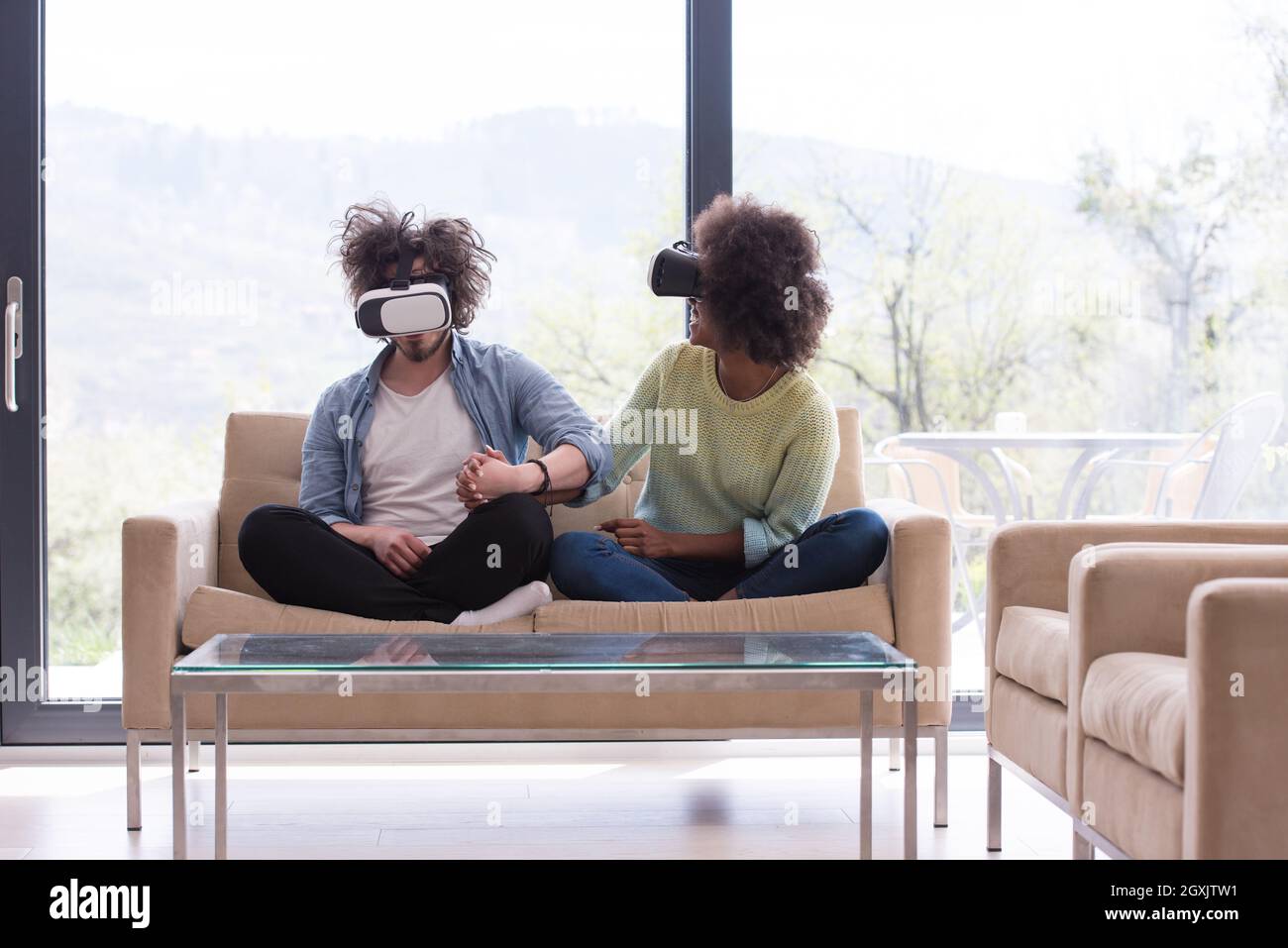 Multiethnic Couple using virtual reality headset in living room at home ...