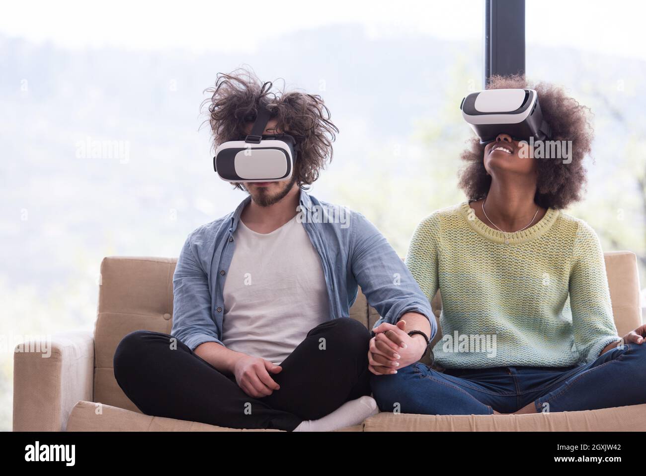 Multiethnic Couple using virtual reality headset in living room at home ...