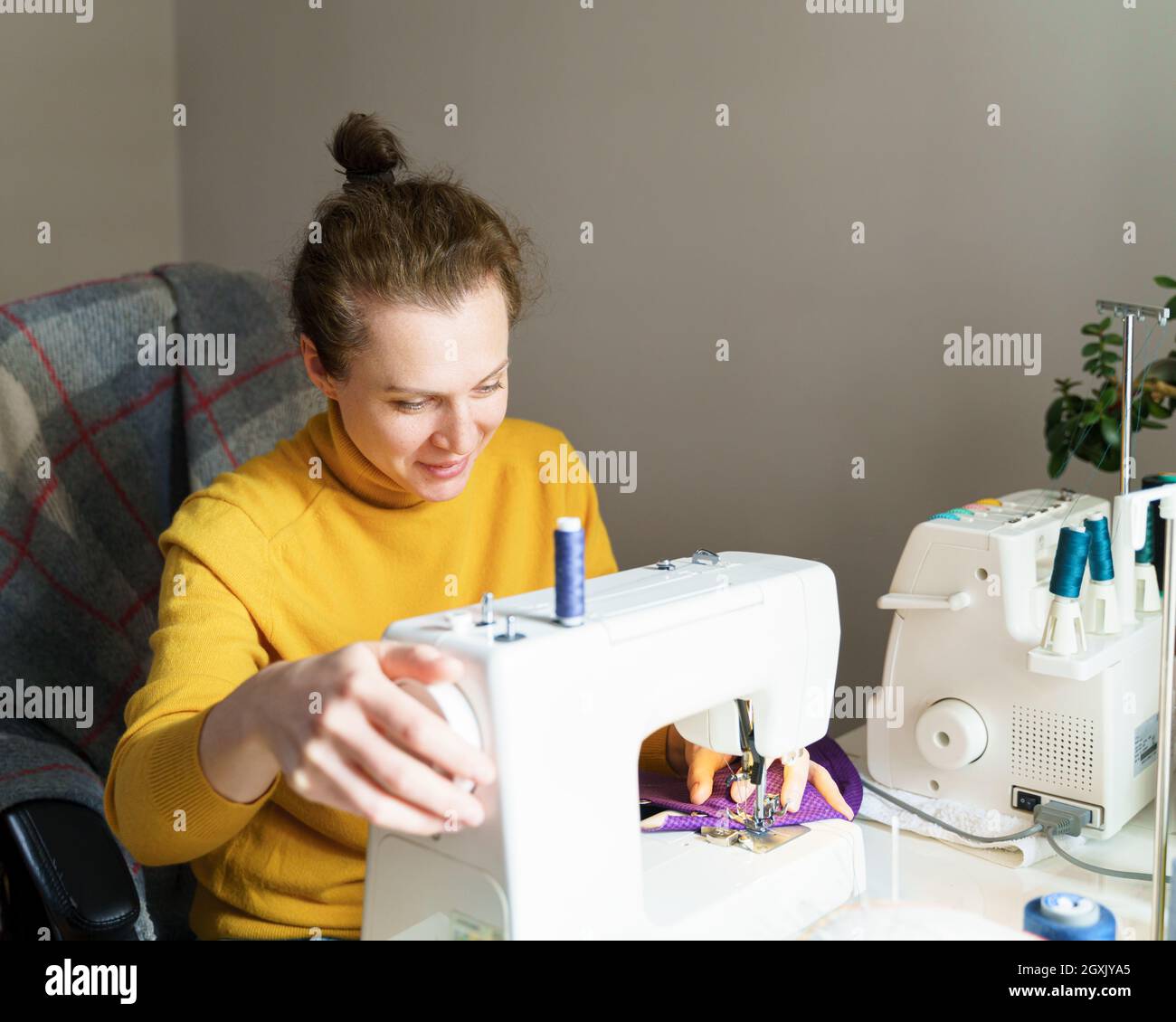 Female seamstress using sewing machine while working at home Stock Photo
