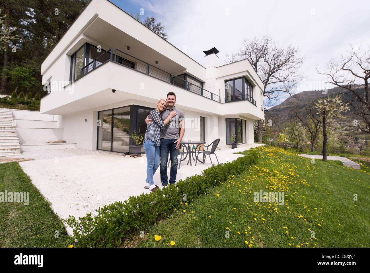 Portrait of a happy young couple hugging in front of their new luxury ...