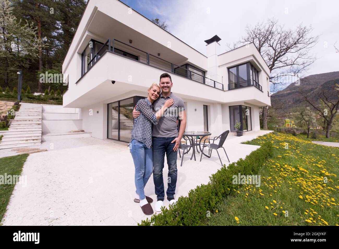 Portrait of a happy young couple hugging in front of their new luxury ...