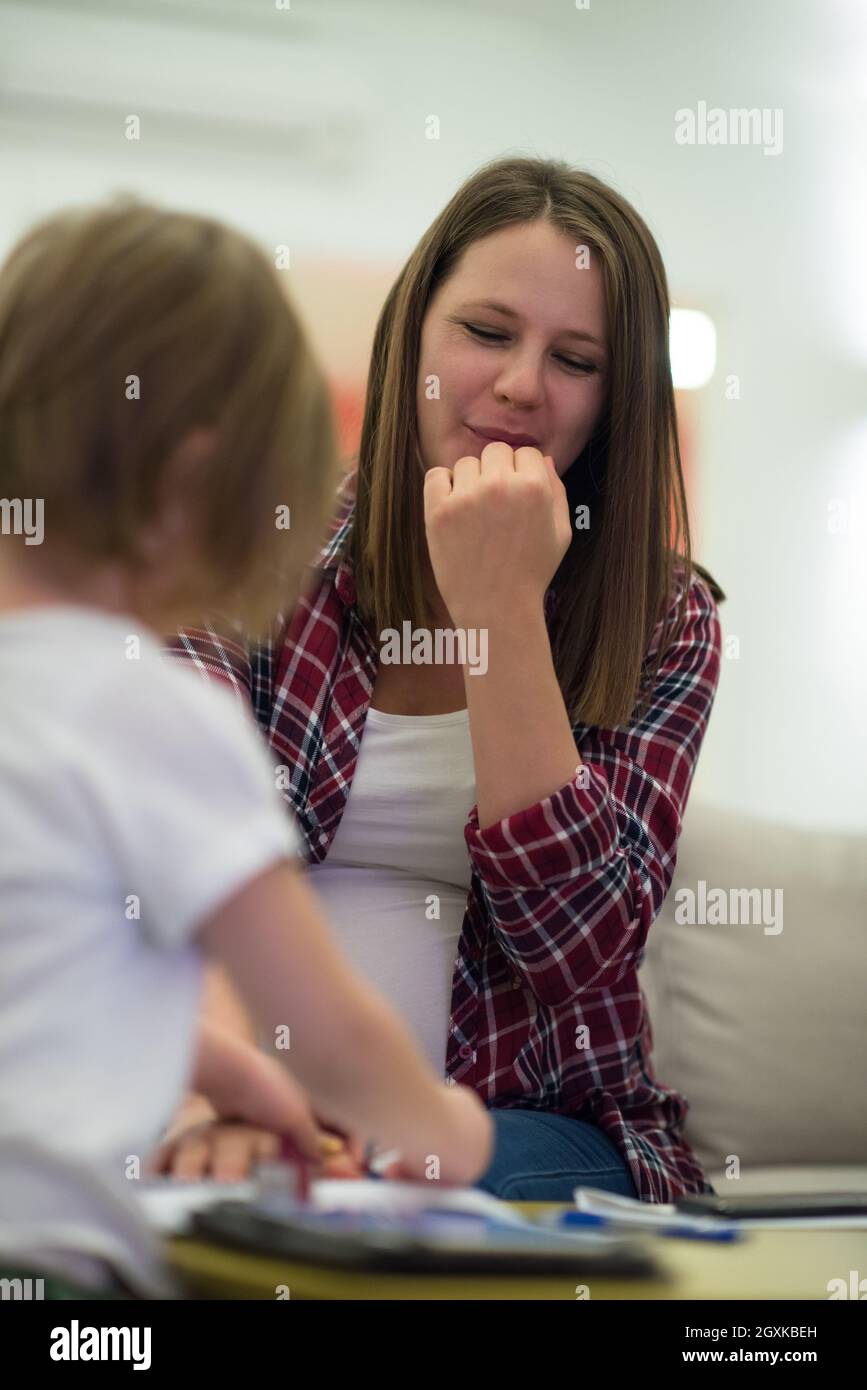 little cute daughter painting nails to her pregnant mom while relaxing