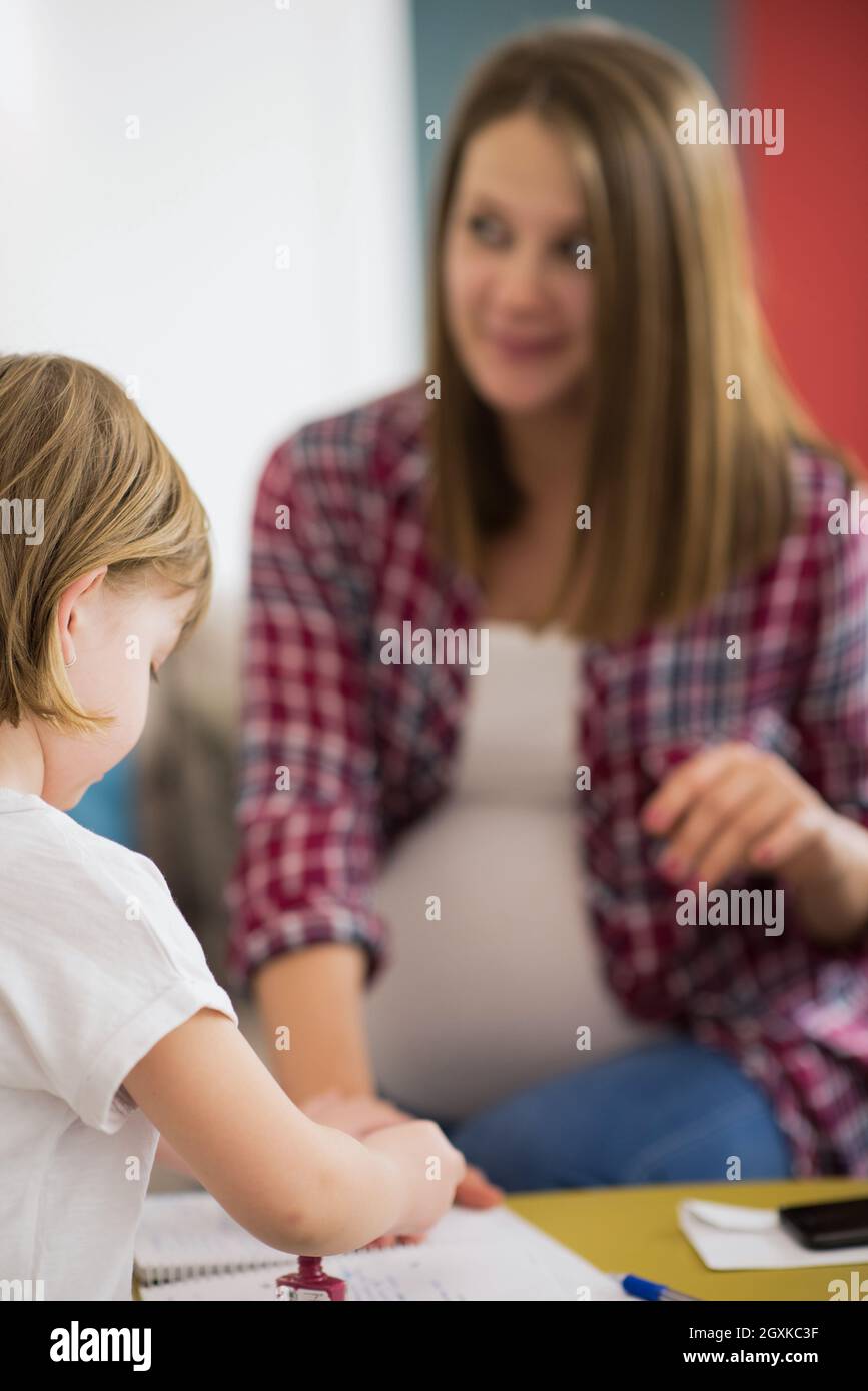 little cute daughter painting nails to her pregnant mom while relaxing at home Stock Photo Alamy