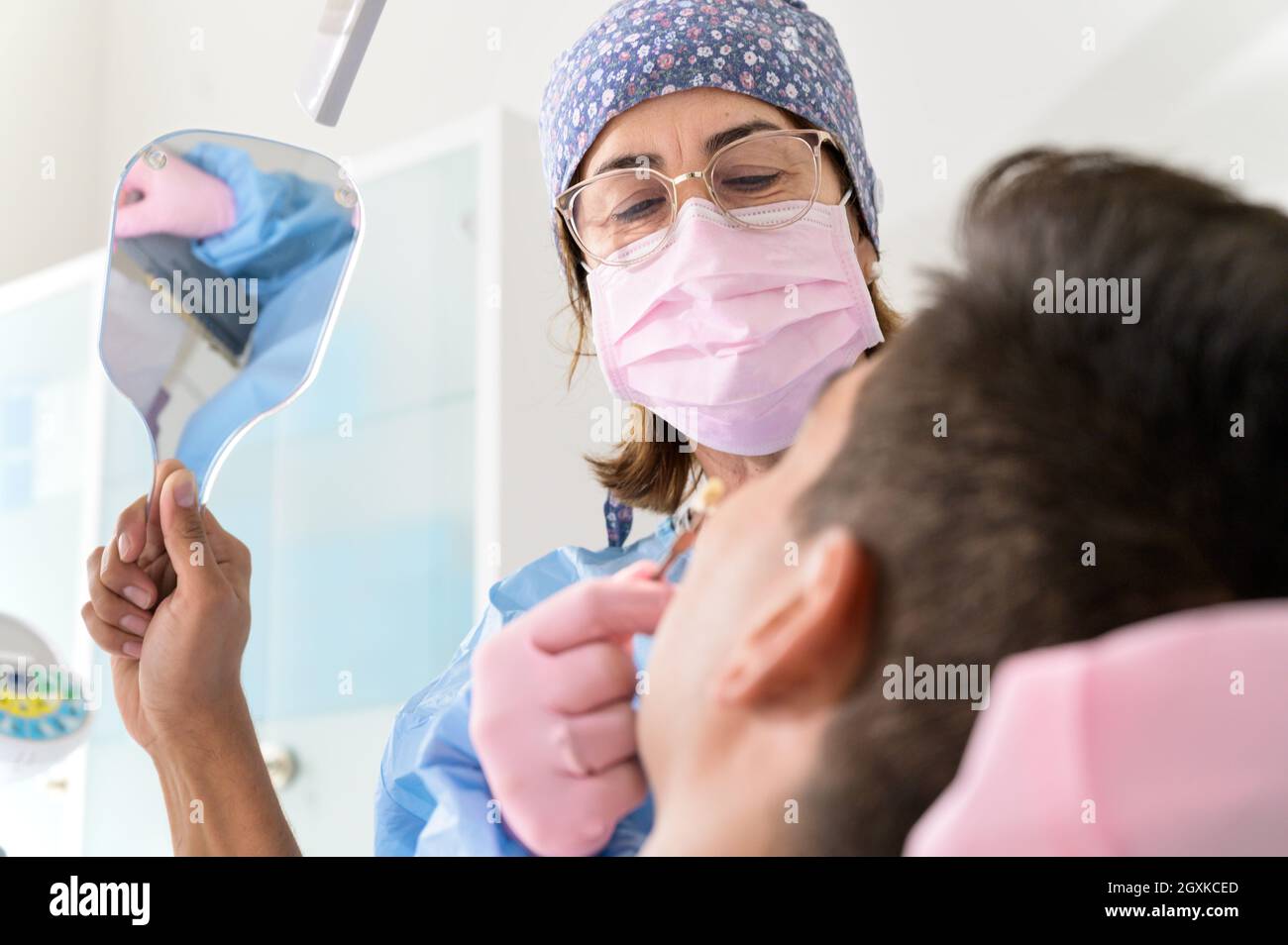 Patient looking teeth in mirror at dental clinic. High quality photo