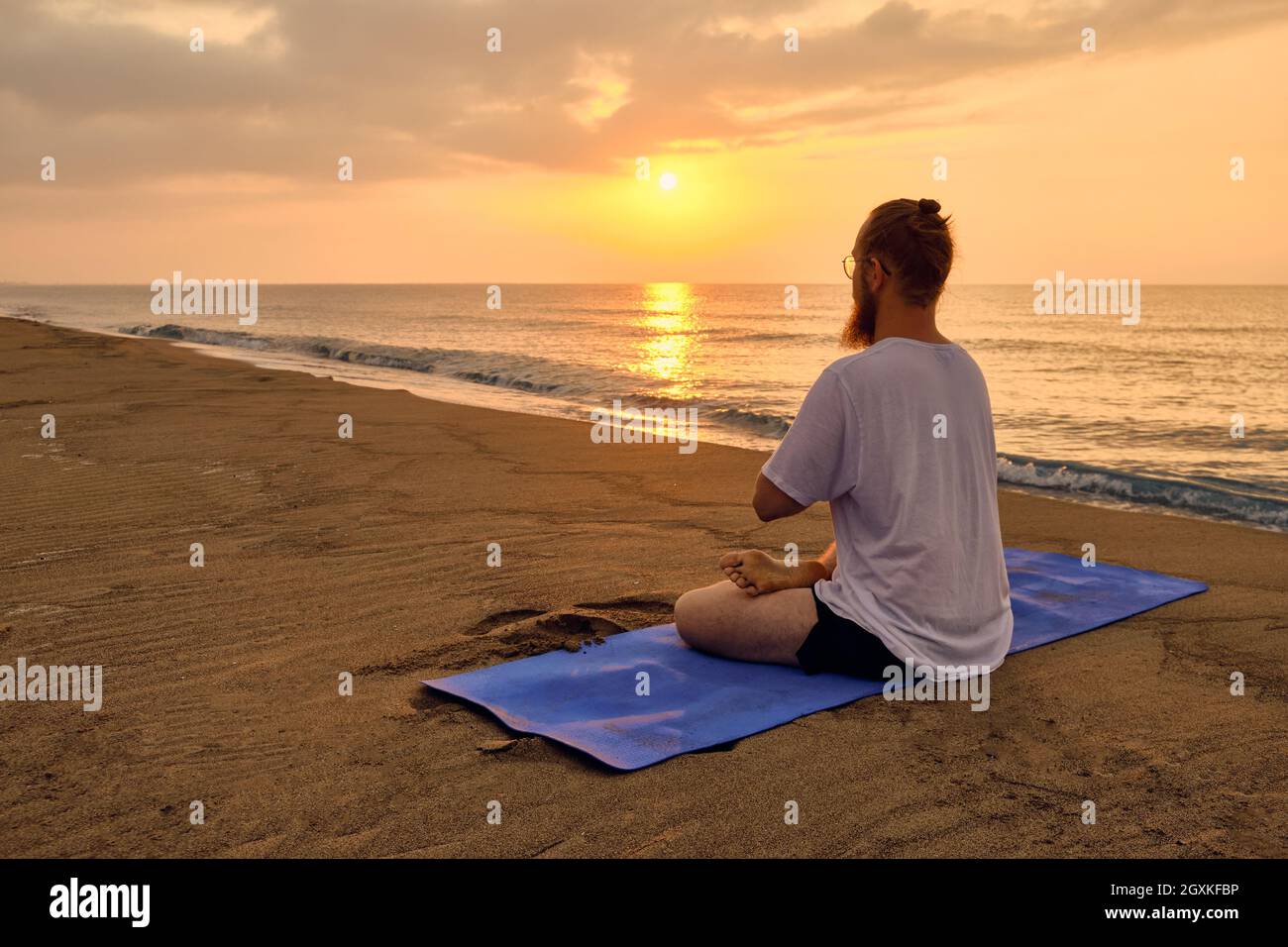 Man sits in lotus position at beach Stock Photo