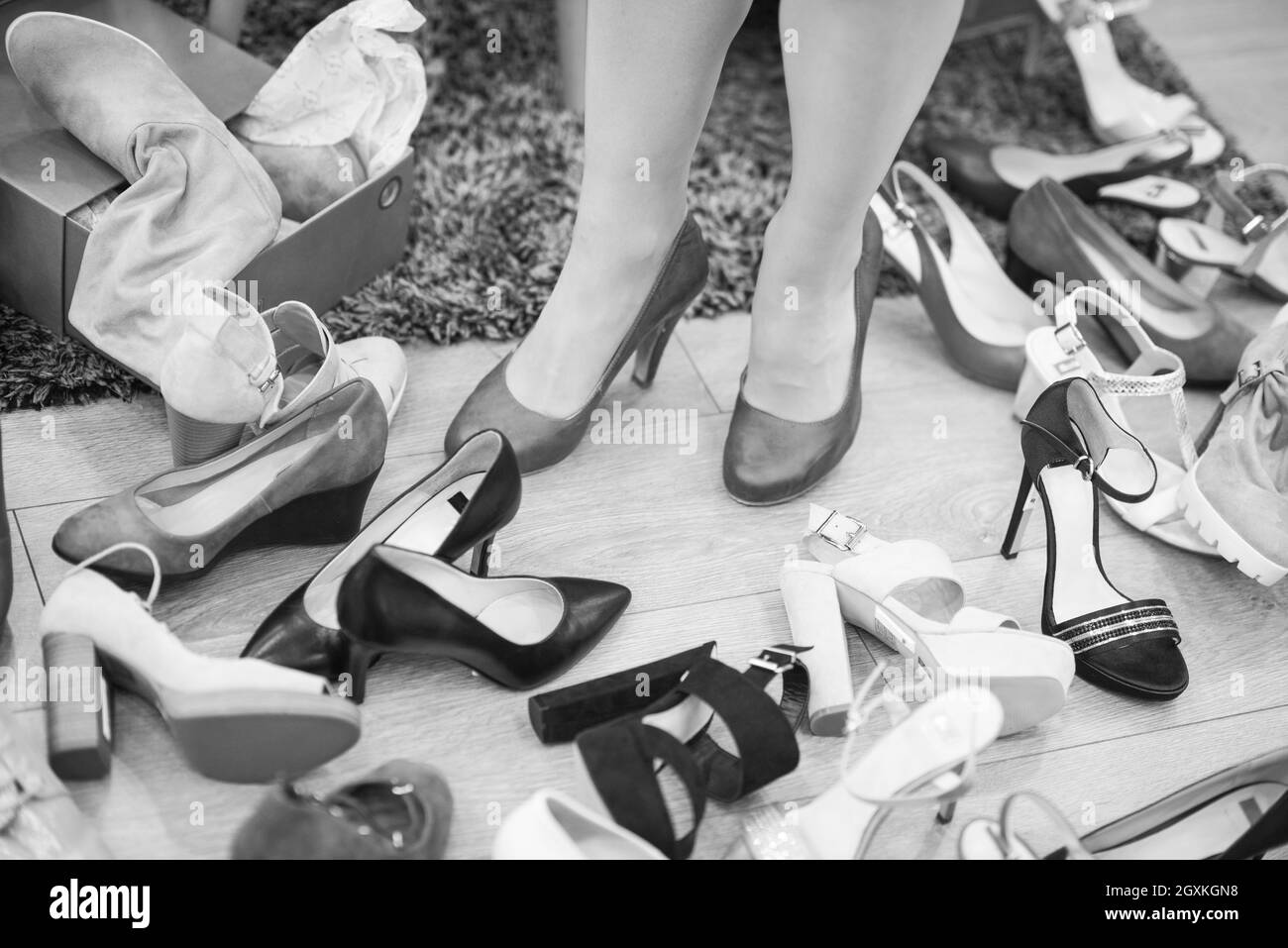 Hard choice. Close-up of young woman sitting in shoe store while different shoes laying near her Stock Photo