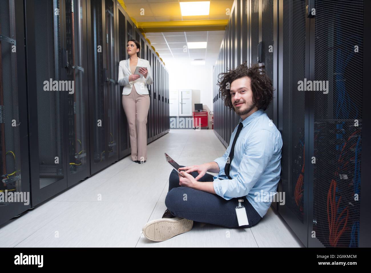 Team of young technicians working together on servers at the data center using tablet computers Stock Photo