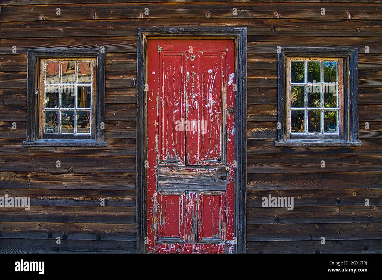Closeup of front door with peeling paint and two windows of an old house of dark wood in the Australian town of Malden Stock Photo