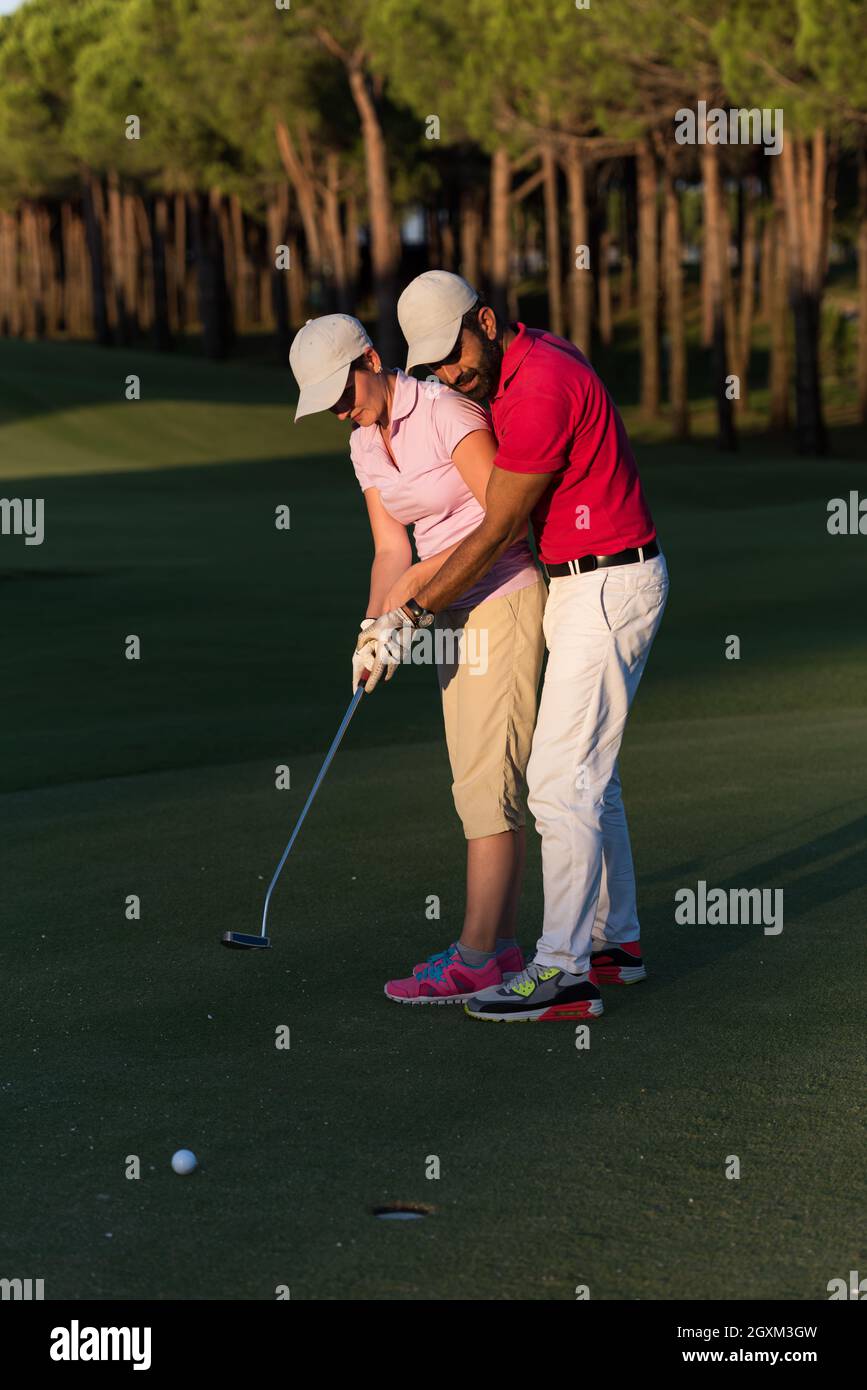 male golf instructor teaching female golf player, personal trainer giving lesson on golf course
