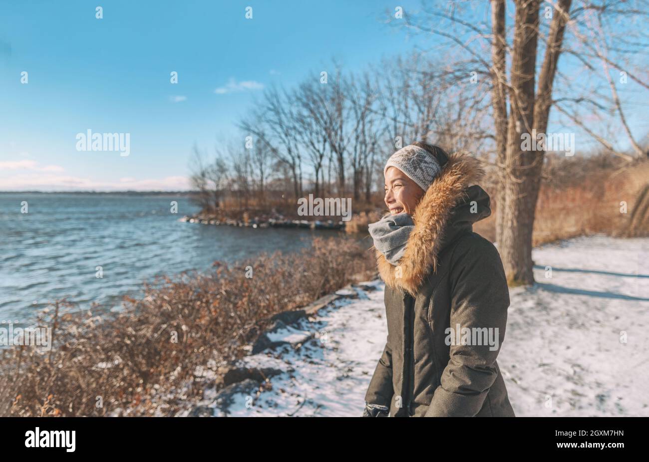 Winter cold Asian woman happy smiling in cold weather on outdoor walk sunlight in forest nature active healthy lifestyle. Young girl enjoying outside Stock Photo