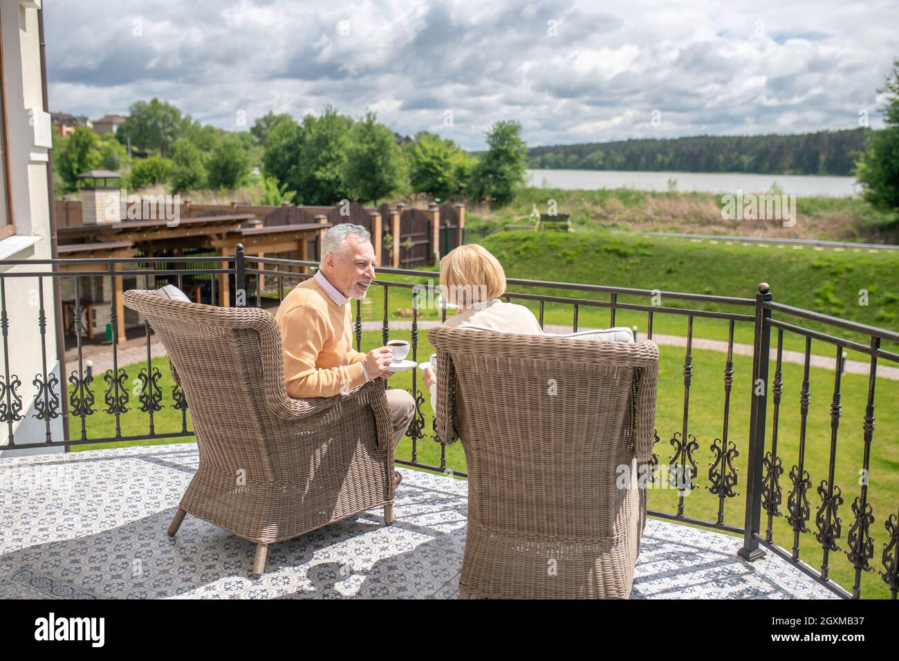 Two people in the wicker arm-chairs sitting on the terrace Stock Photo ...