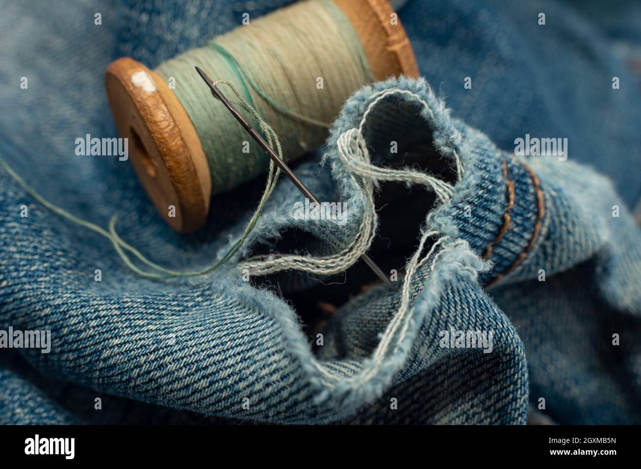 Hole in jeans. Needle with thread for darning jeans. Tools for work