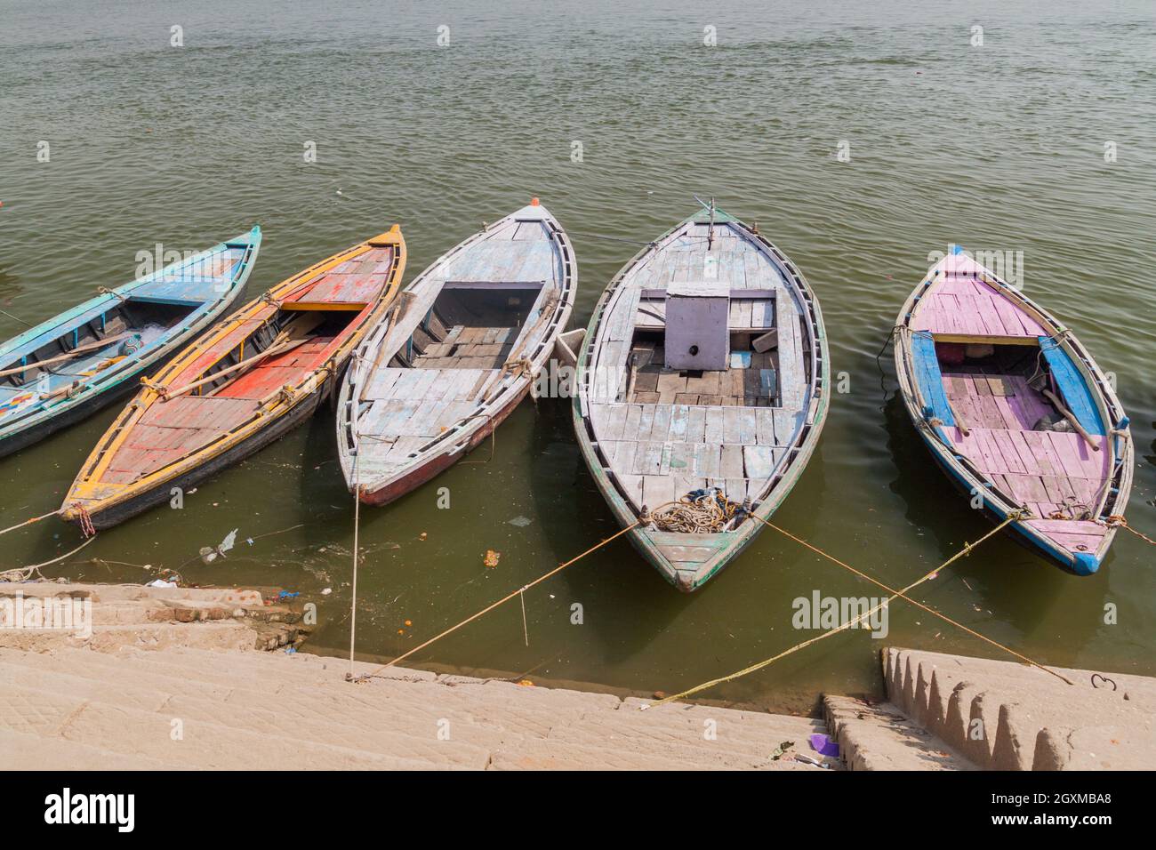 Small boats near Ghats riverfront steps leading to the banks of the River Ganges in Varanasi, India Stock Photo