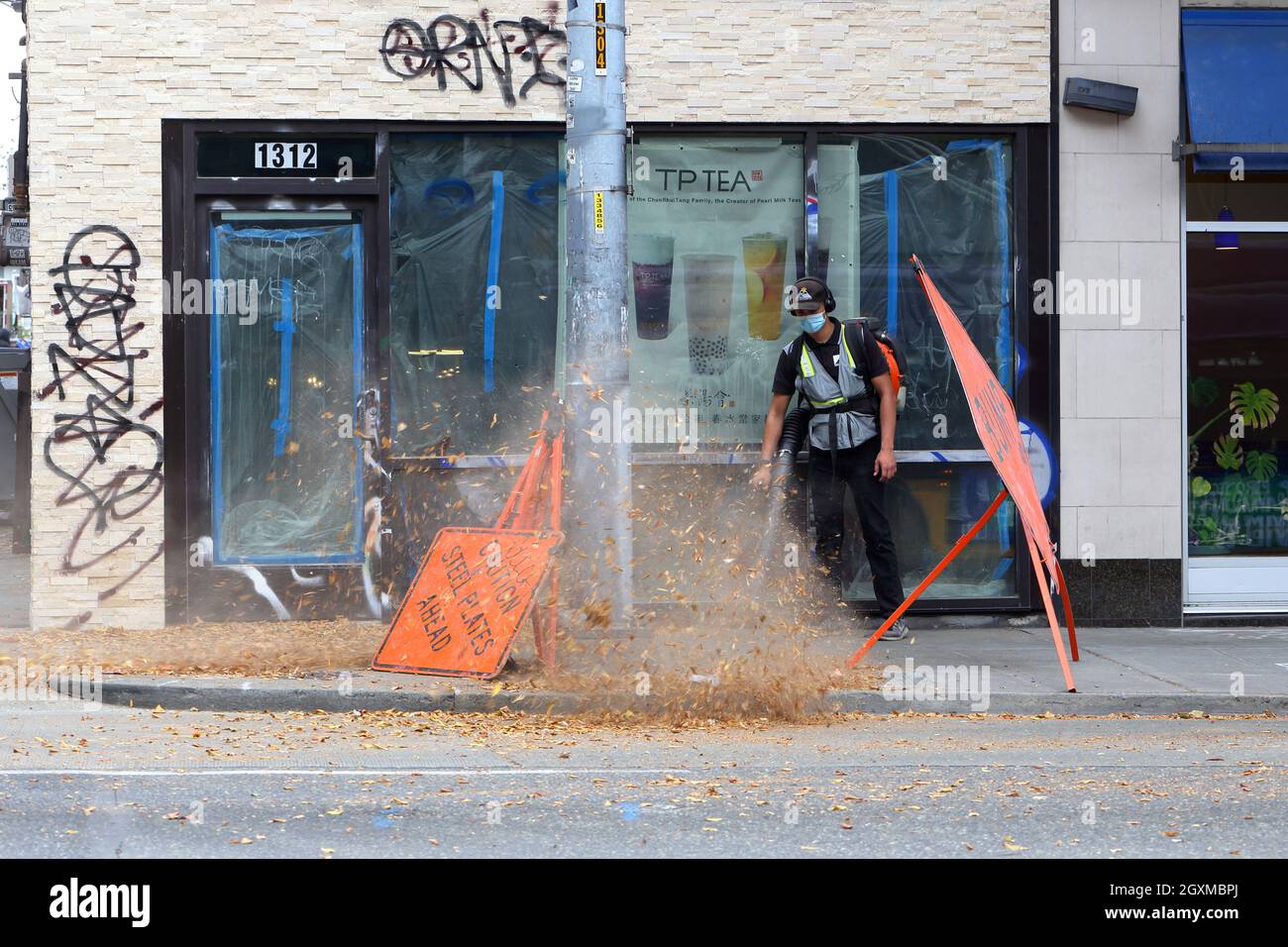 A person with a gas powered leaf blower blows leaves off a sidewalk in the U District in Seattle ... [see additional info for the full caption] Stock Photo