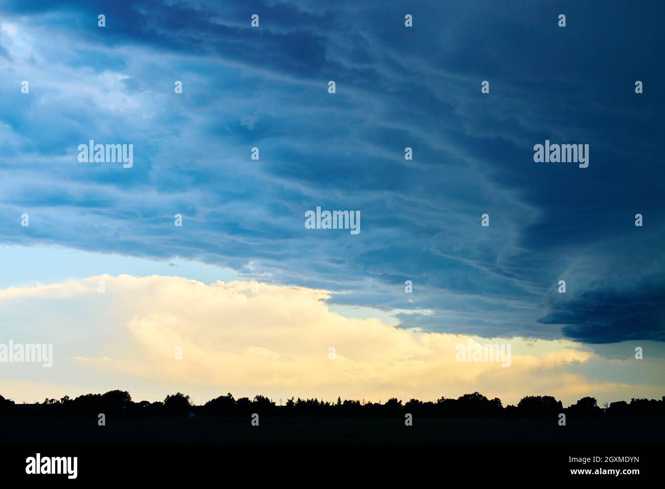 Large storm clouds over silhouette of forest and farmland Stock Photo ...
