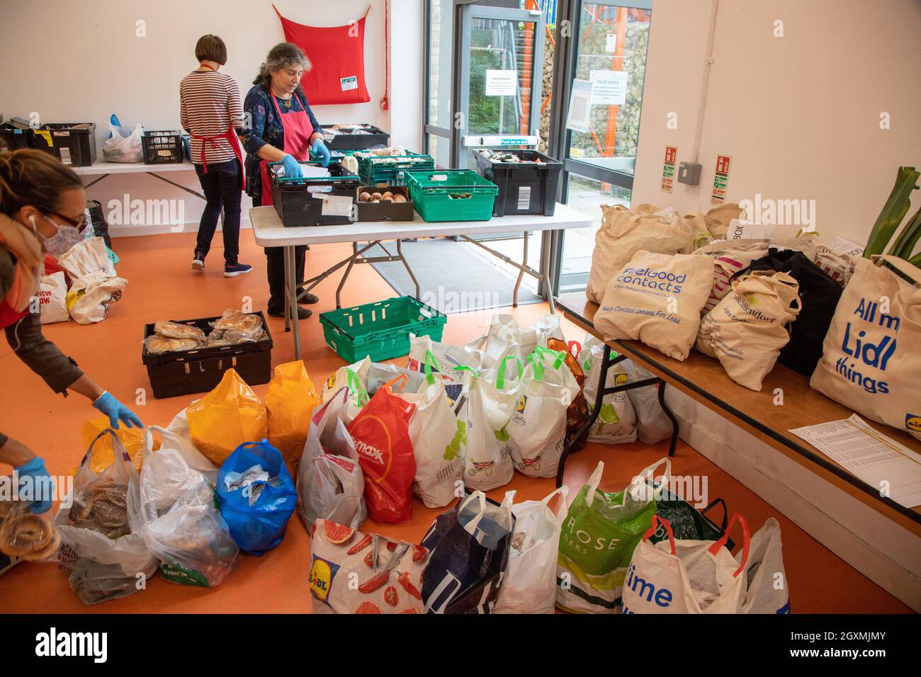 Three women volunteers at a food bank sorting crates of donated food in