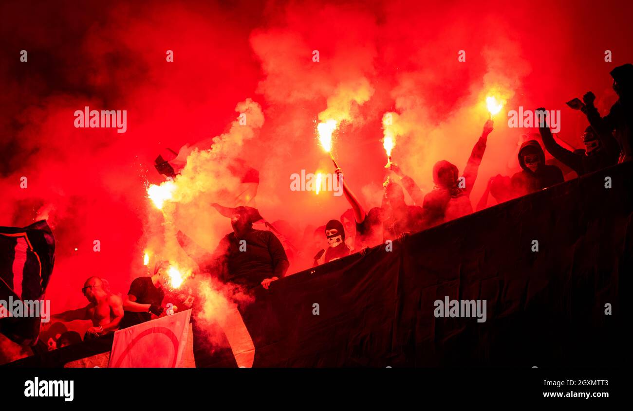 football hooligans with mask holding torches in fire while supporting their favorite team during a match at stadium Stock Photo