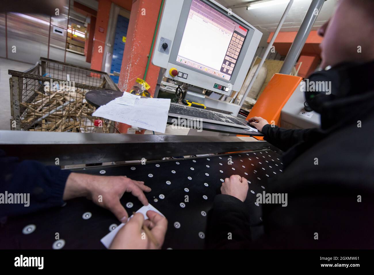 two young carpenters calculating and programming a cnc wood working machine in workshop. wood workers preparing a computer program for CNC machine at Stock Photo