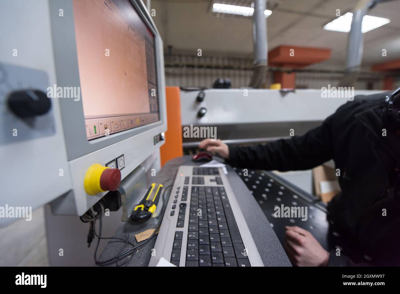two young carpenters calculating and programming a cnc wood working machine in workshop. wood workers preparing a computer program for CNC machine at Stock Photo