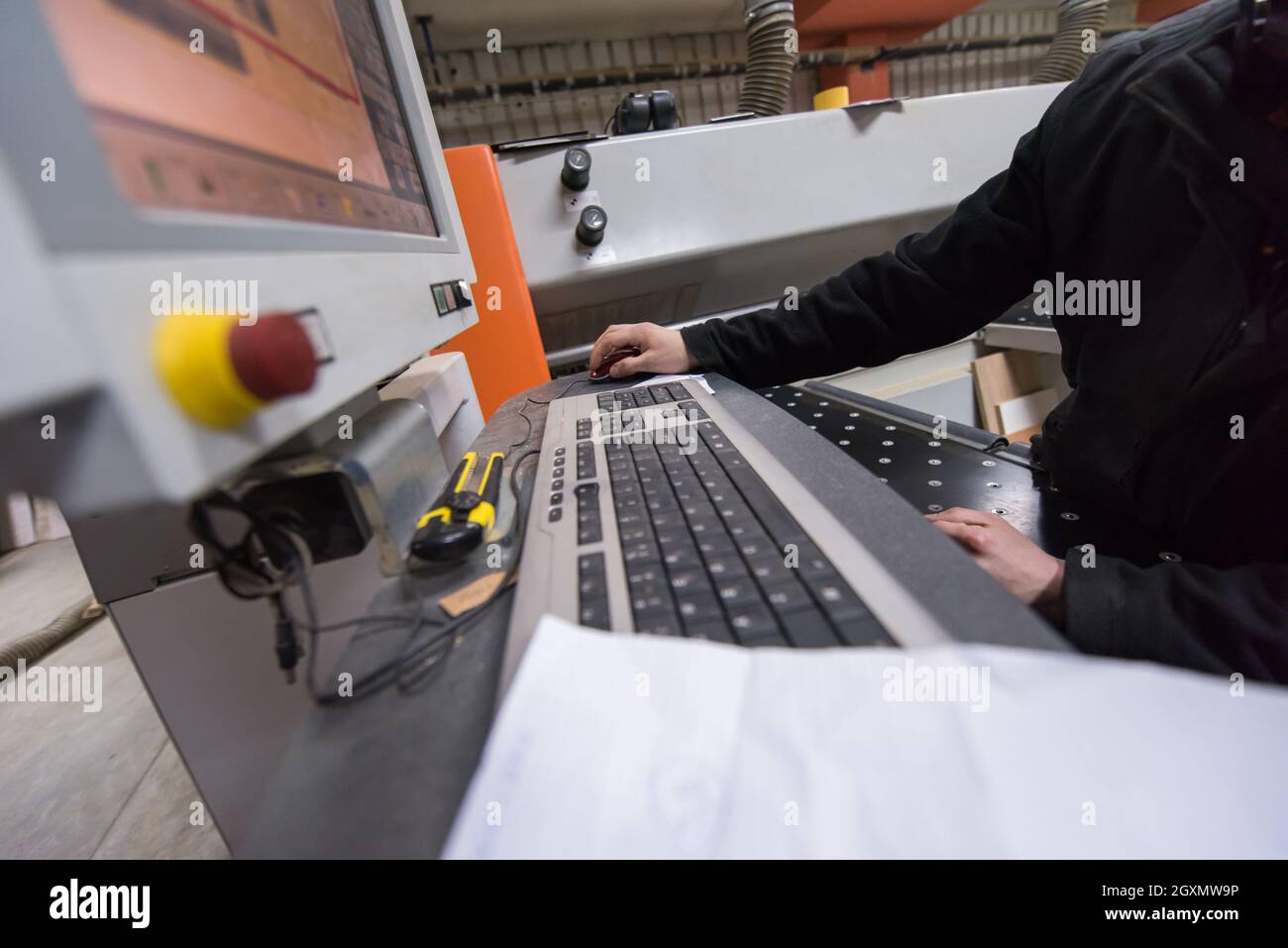 two young carpenters calculating and programming a cnc wood working machine in workshop. wood workers preparing a computer program for CNC machine at Stock Photo