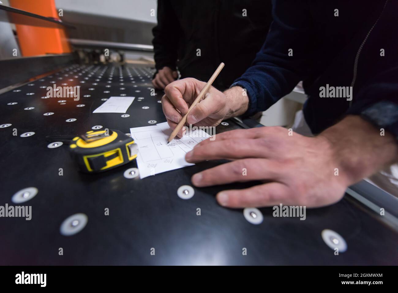two young carpenters calculating and programming a cnc wood working machine in workshop. wood workers preparing a computer program for CNC machine at Stock Photo