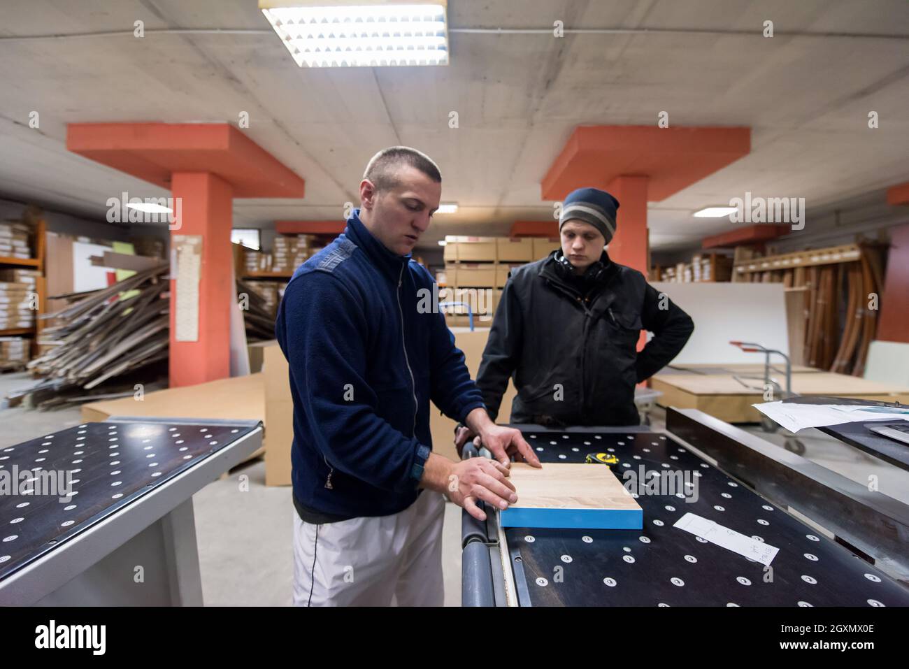 two young carpenters calculating and programming a cnc wood working machine in workshop. wood workers preparing a computer program for CNC machine at Stock Photo