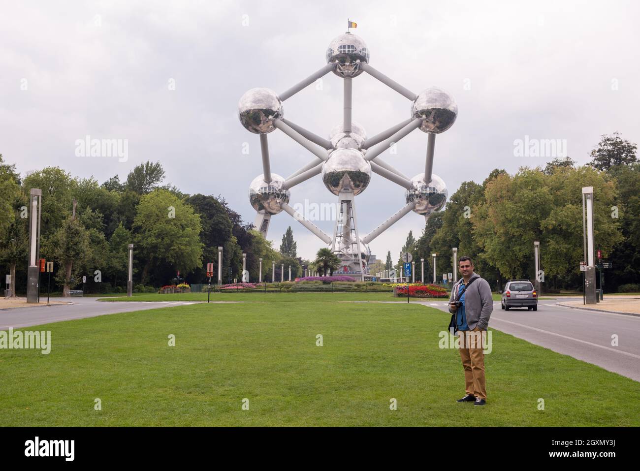 a portrait of a male tourist standing in front of Atomium building in ...