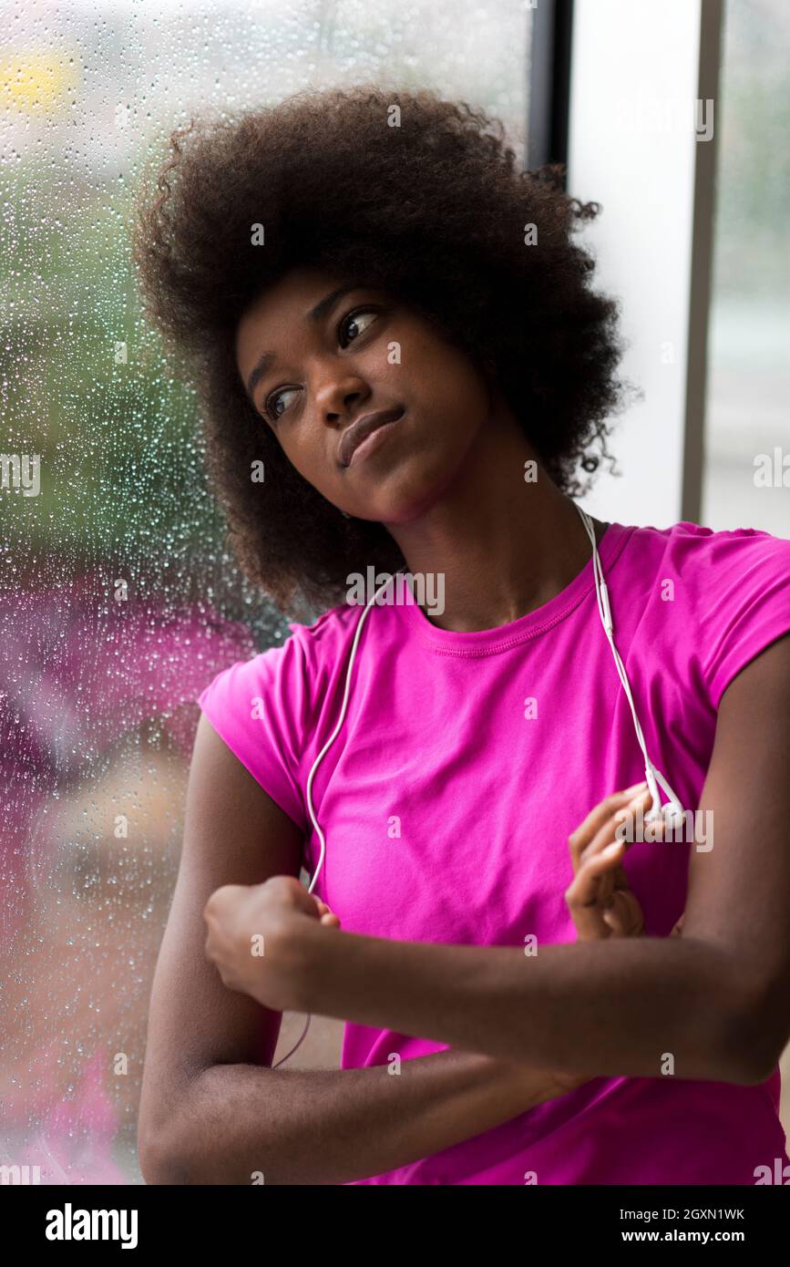 portrait of young afro american woman in gym on workout break while  listening music on earphone and dancing rainy day and bad weather outdooor  Stock Photo - Alamy