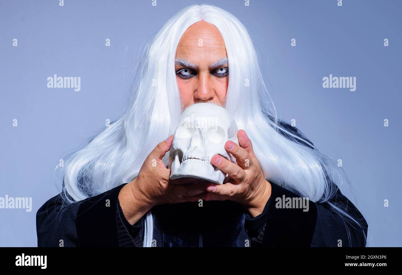 Halloween demon. Devil man with skull. Sorcerer with white eyes and hair. Horror and Scary concept Stock Photo