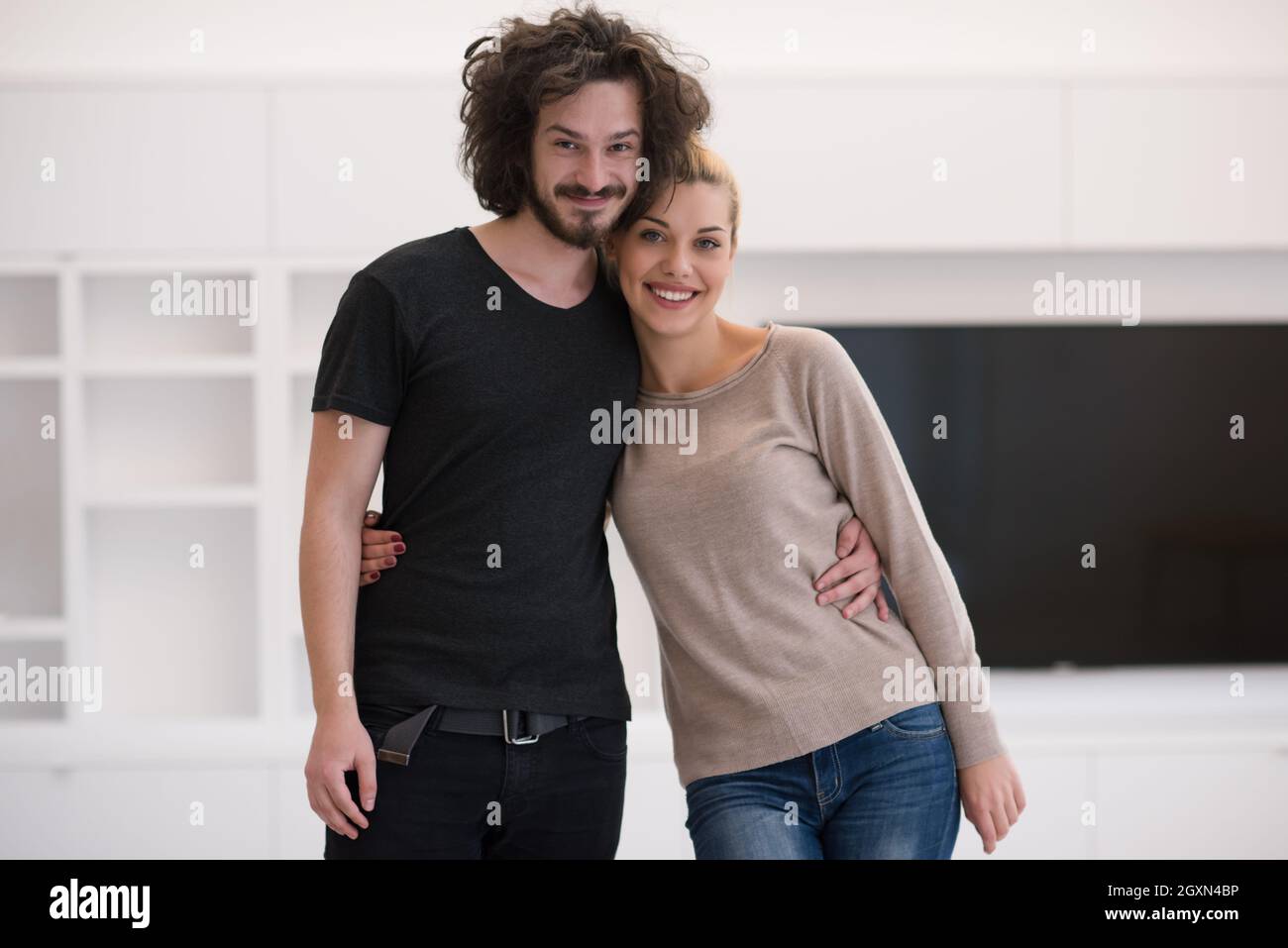 Portrait of a happy young beautiful couple hugging in their new home ...