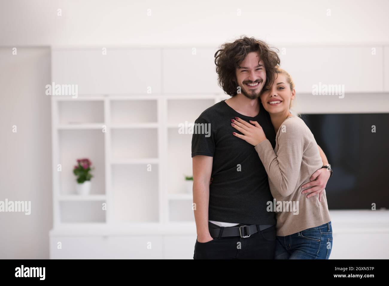 Portrait of a happy young beautiful couple hugging in their new home ...