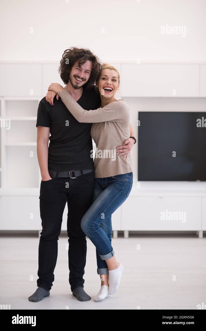 Portrait of a happy young beautiful couple hugging in their new home ...