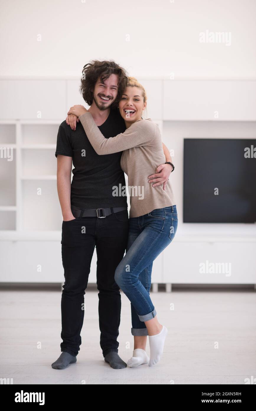 Portrait of a happy young beautiful couple hugging in their new home ...
