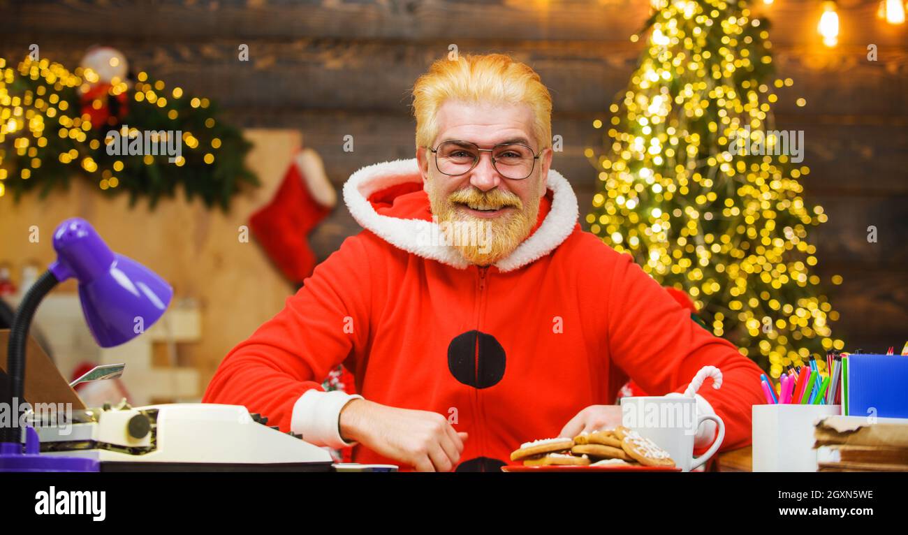 Smiling Santa Claus sitting at table. Christmas decorations. Merry Christmas and Happy New Year Stock Photo